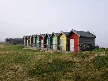 Huts on field by building against clear sky