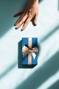 Woman's hand reaching for box with gift inside in sunlight.