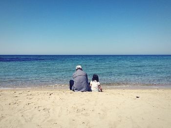 Rear view of woman sitting on beach