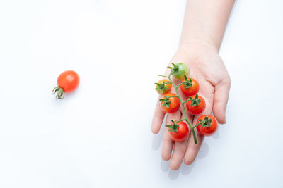 Close-up of hand holding strawberry over white background