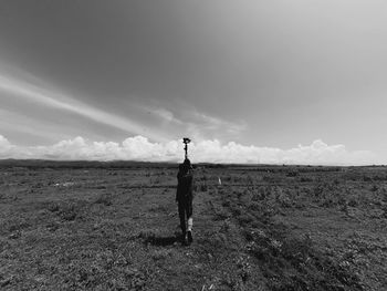 Rear view of man walking on field against sky