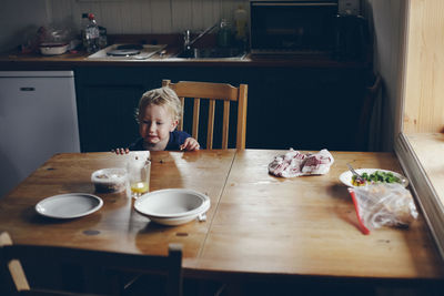 Boy by food and drink on table at home