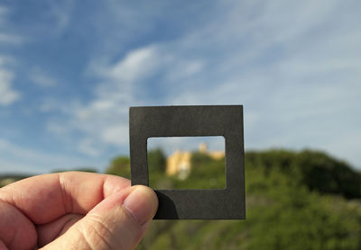 Close-up of man holding frame against sky