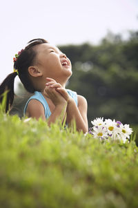 Girl with bunch of flowers lying on grassy field at park