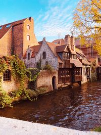 Buildings by river against sky