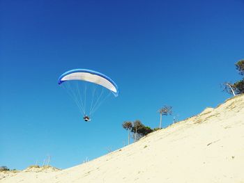 Low angle view of person paragliding against clear blue sky