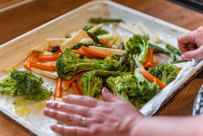 Close-up photo of woman putting mixed vegetables on baking tray
