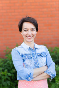 Portrait of young woman standing against wall