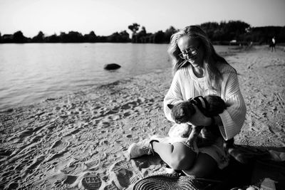 Smiling woman with cat sitting at lakeshore