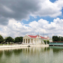 Building by lake against cloudy sky