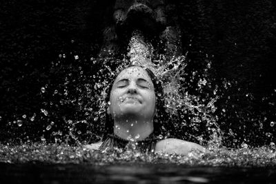 Young woman splashing water in pool