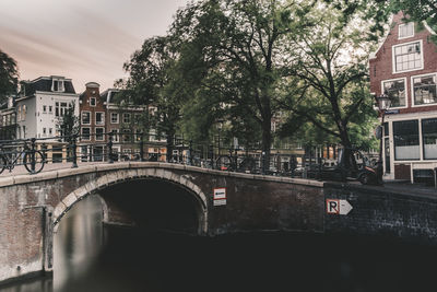 Arch bridge over canal amidst buildings in city