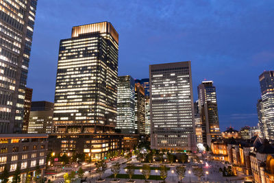 Illuminated buildings in city against sky at dusk