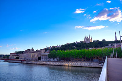 Buildings at waterfront against cloudy sky