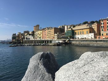 Buildings by sea against clear blue sky