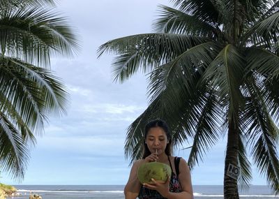 Young woman sitting on beach against sky