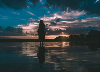 Silhouette woman standing against sea during sunset