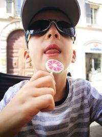 Low angle view of boy eating lollypop against building