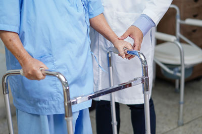 Midsection of doctor helping patient with walker