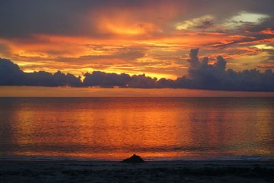 Scenic view of sea against dramatic sky during sunset