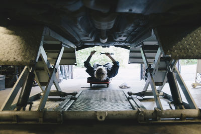 Underneath view of female mechanic repairing car at auto repair shop