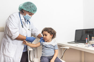 Vaccination concept. female doctor vaccinating cute little boy on blue background, closeup.