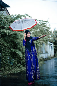 Rear view of woman with umbrella walking on road