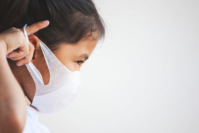 Side view of girl wearing mask against white background