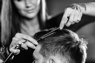 Close-up of woman cutting man hair at shop