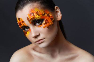 Portrait of woman with decorated face make-up against black background