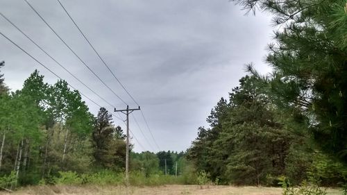 Electricity pylon against cloudy sky