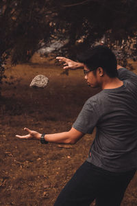 Side view of young man standing on field