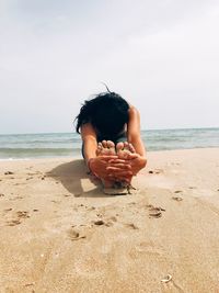 Midsection of woman on beach against sky