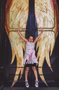 Full length portrait of smiling girl standing outdoors