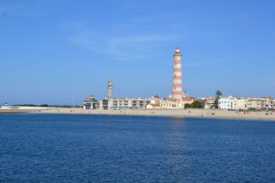 Tower by sea against blue sky