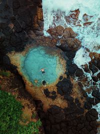 Aerial view of man floating on tidal pool