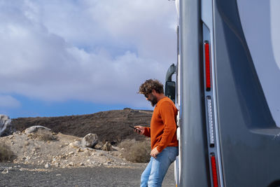 Rear view of man standing on car