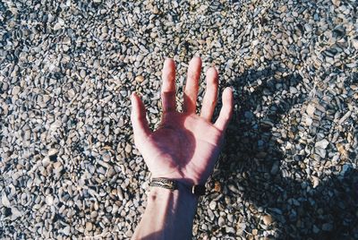 High angle view of hand on pebbles at beach