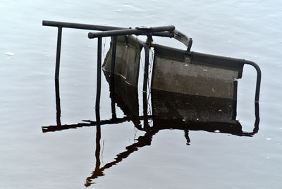 Discarded chair lying on side in water