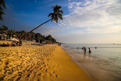 People on beach against sky during sunset