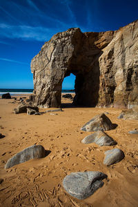 Rock formations at beach against sky