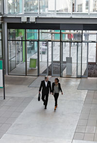 High angle view of male and female business professionals walking in atrium at office