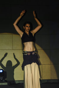 Full length of young woman standing against wall at home