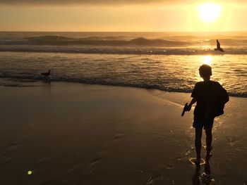 Silhouette of boy at beach during sunset