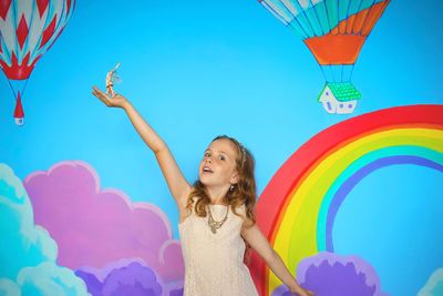 Full length of smiling girl against blue sky