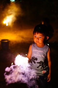 Close-up of boy holding sparkler at night