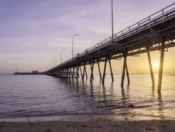 Bridge over sea against sky during sunset