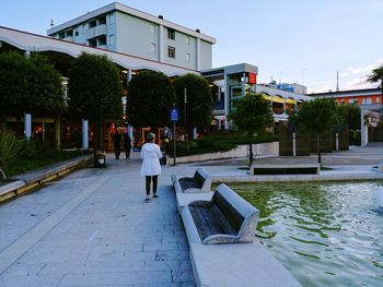 Rear view of man walking on street by buildings in city