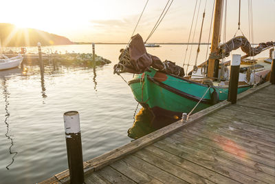 Fishing boat moored at pier against sky during sunset