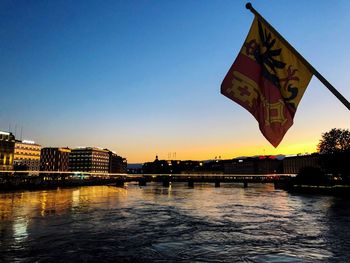 River by buildings against clear sky during sunset